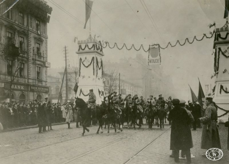 Wkroczenie oddziałów legionowych do Warszawy. Wojska przejeżdżają przez bramę triumfalną w Alejach Jerozolimskich. Na czele konno ppłk Witold Rylski ps. „Ścibor”. 1.12.1916 r. Źródło: CAW