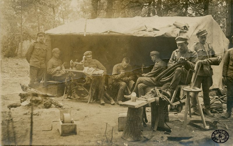 Warsztat intendentury I Brygady Legionów Polskich w lesie pod namiotem. Krawiec, szewcy i rymarz przy pracy. Wołyń. Lato 1916 r. Źródło: CAW